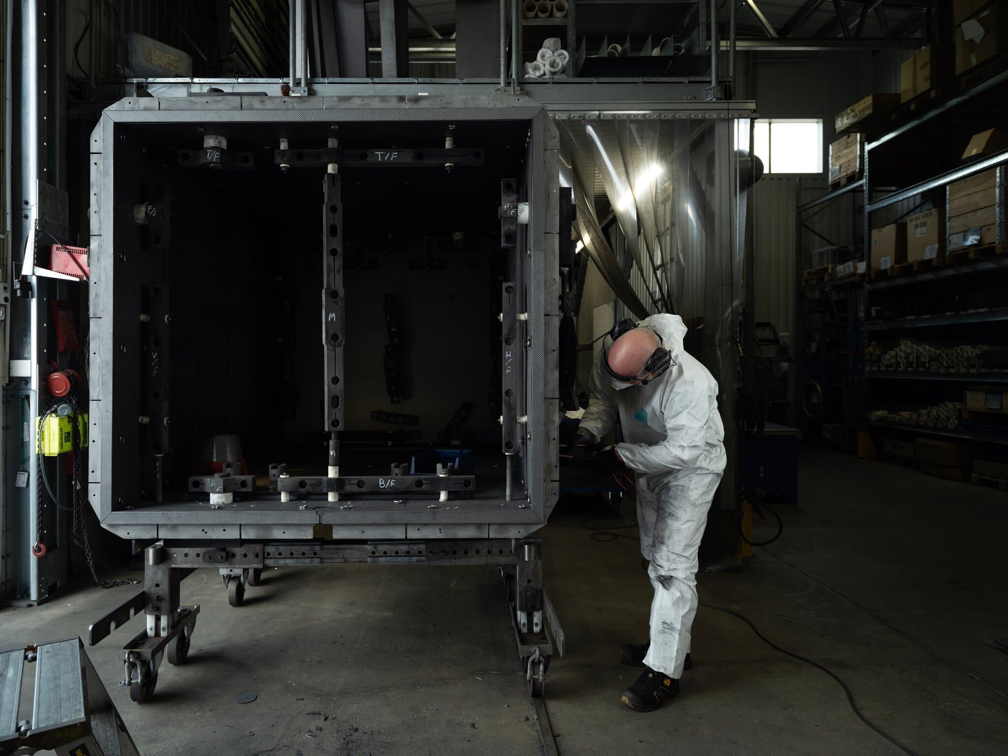Person performing heating chamber reconditioning of vacuum furnace in workshop environment